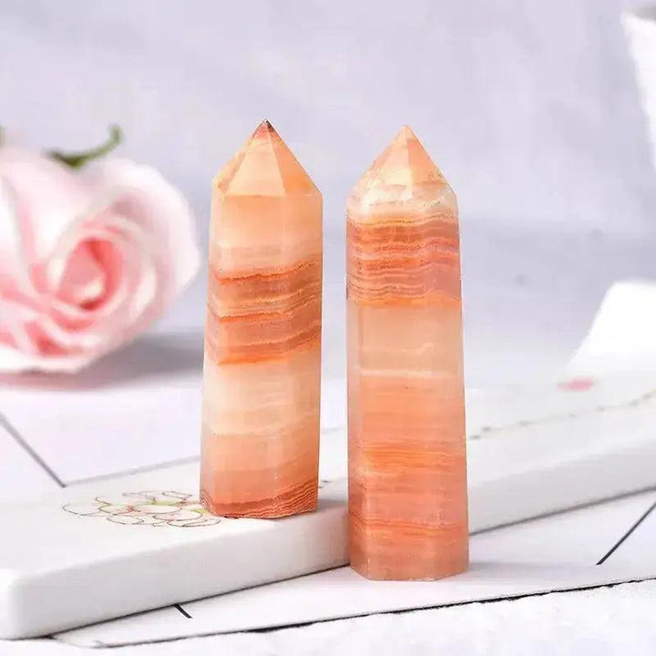 Two polished orange calcite crystal towers, showcasing natural bands and pointed tops, ideal for energy work and decor.