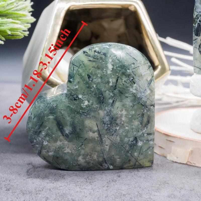 Polished apple green Prehnite heart crystal with natural black inclusions, perfect for calming meditation and healing.