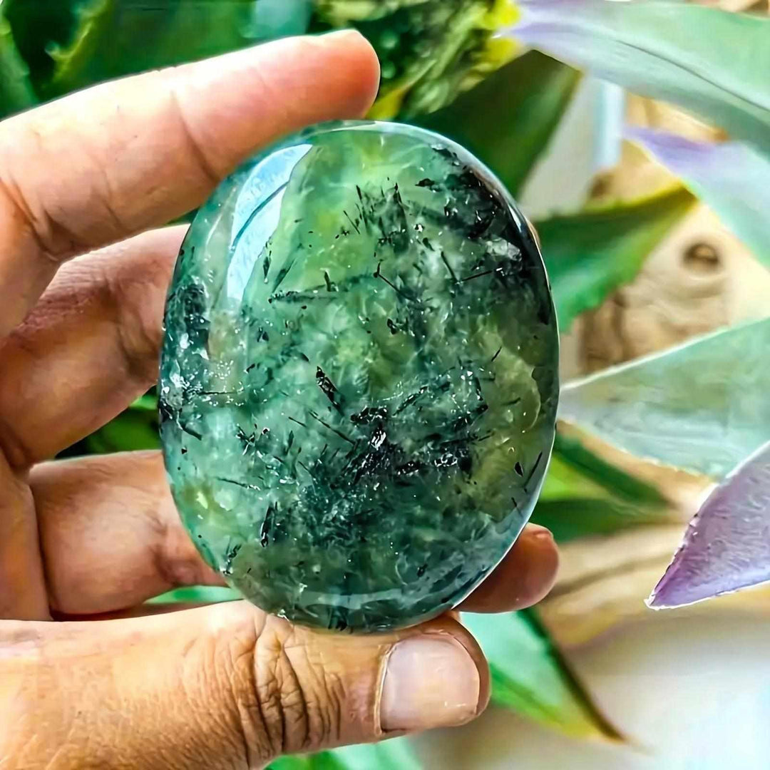 Polished apple green Prehnite palm stone with natural black inclusions, perfect for meditation and calming energy.