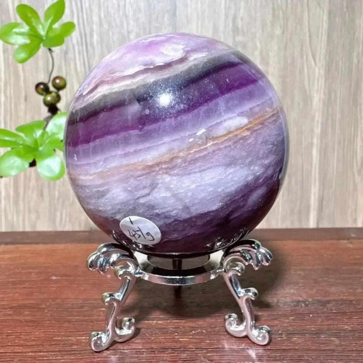 Polished purple fluorite crystal sphere with deep violet banding, perfect for third eye chakra clarity and energy healing.