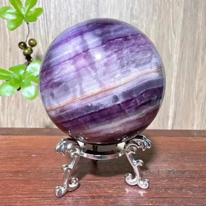 Polished purple fluorite crystal sphere with deep violet banding, perfect for third eye chakra clarity and home decor.