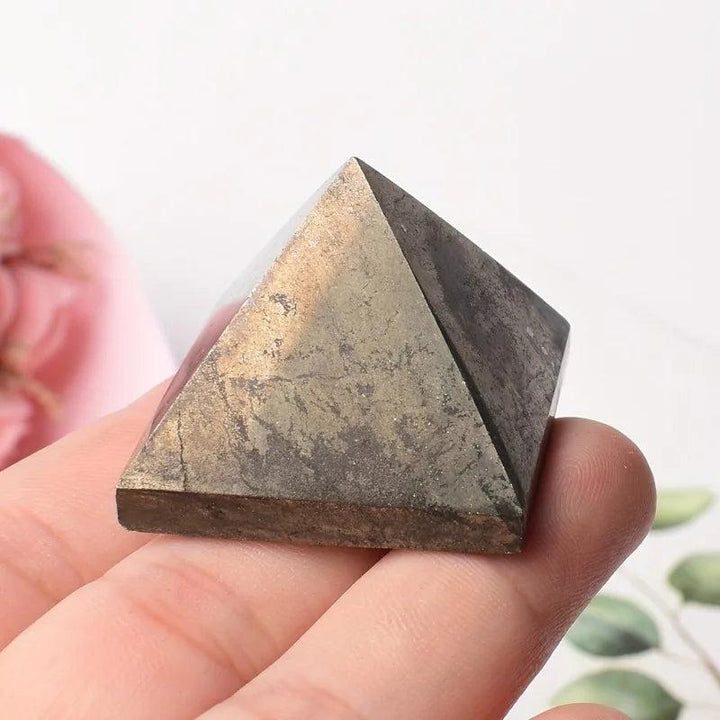 Metallic gold Pyrite Crystal Pyramid for manifestation, abundance, and confidence, held in a hand.