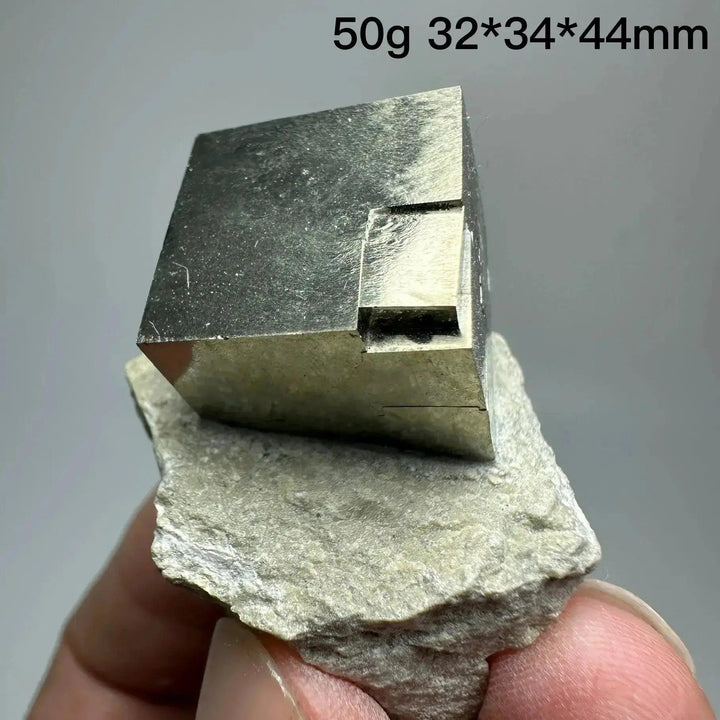 Metallic gold Pyrite Cube Crystal Specimen from Crystal Destiny, naturally formed on a light gray matrix.