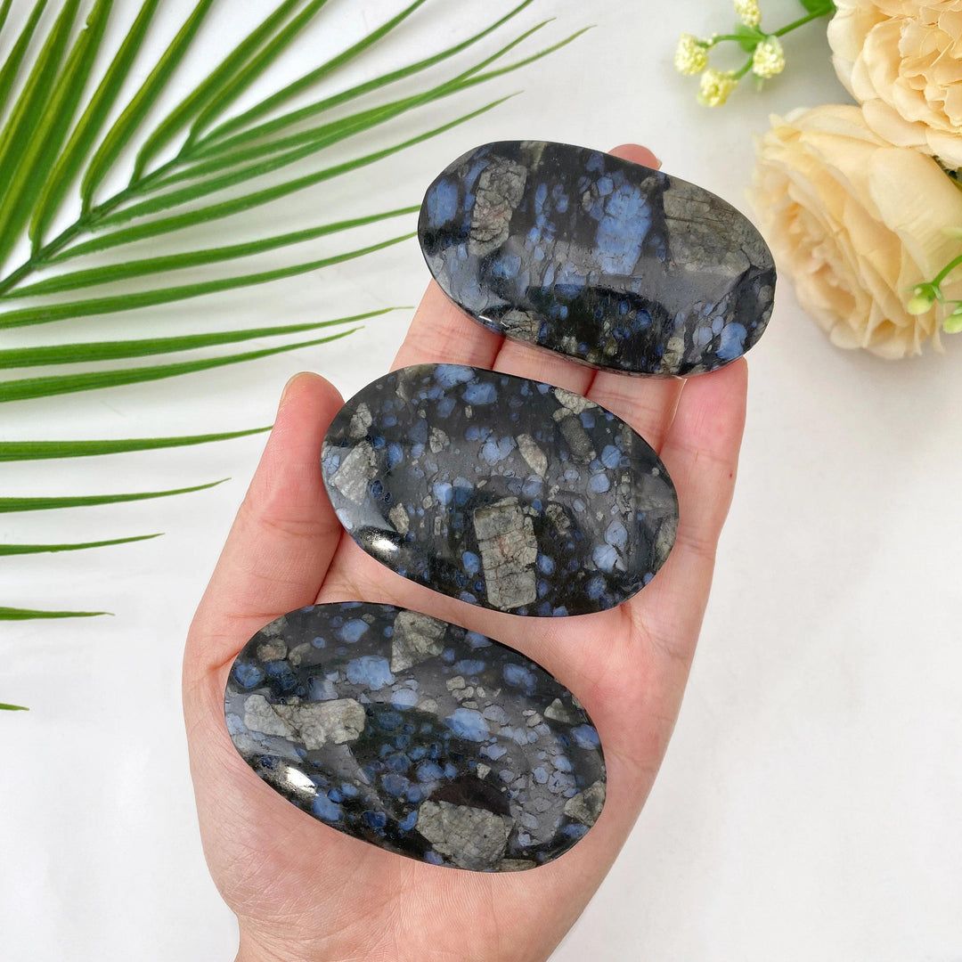 Polished natural Que Sera stone oval palm stones with healing blue and grey flecks.