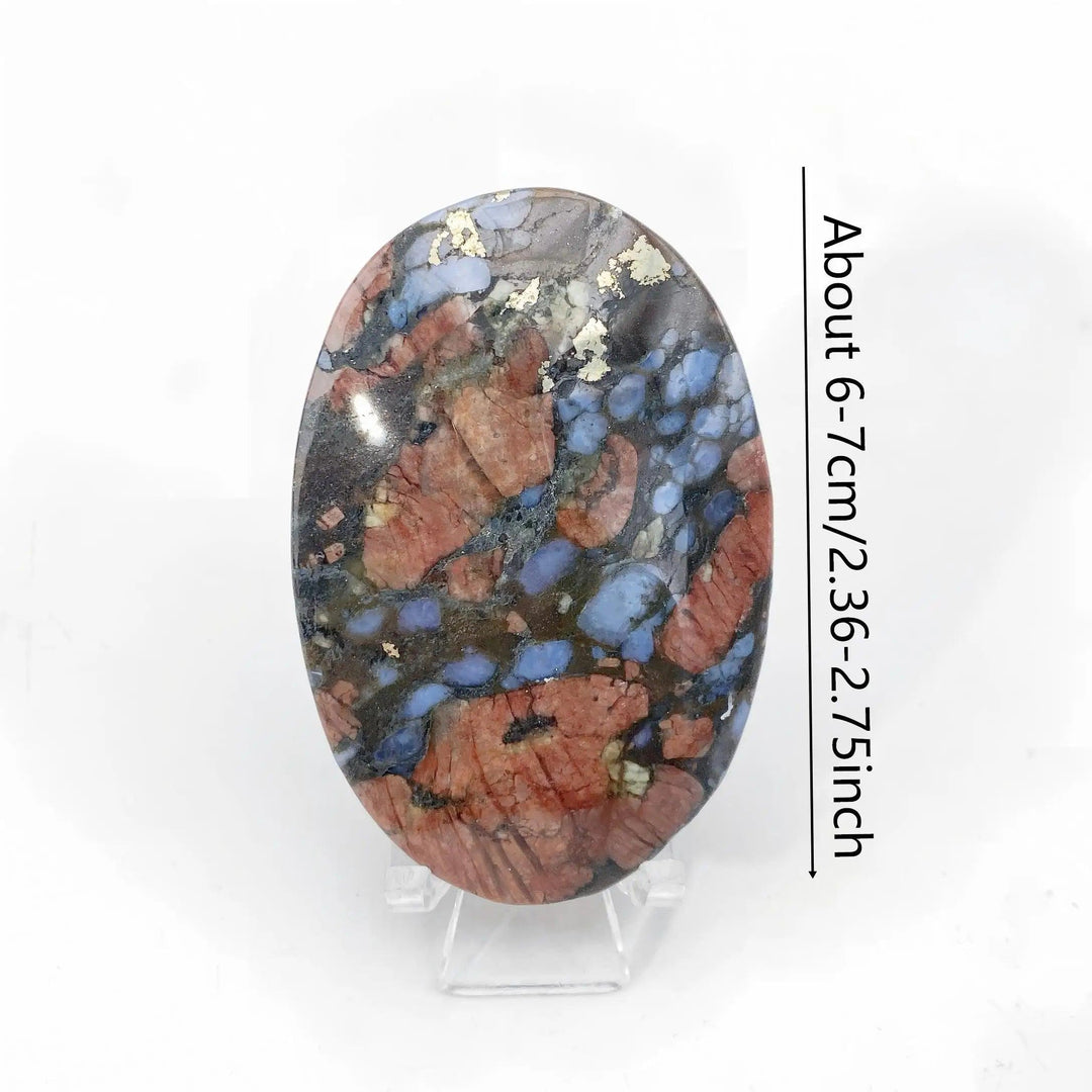 Polished Que Sera stone oval palm stone with blue, pink, and gold flecks for healing and home decor.