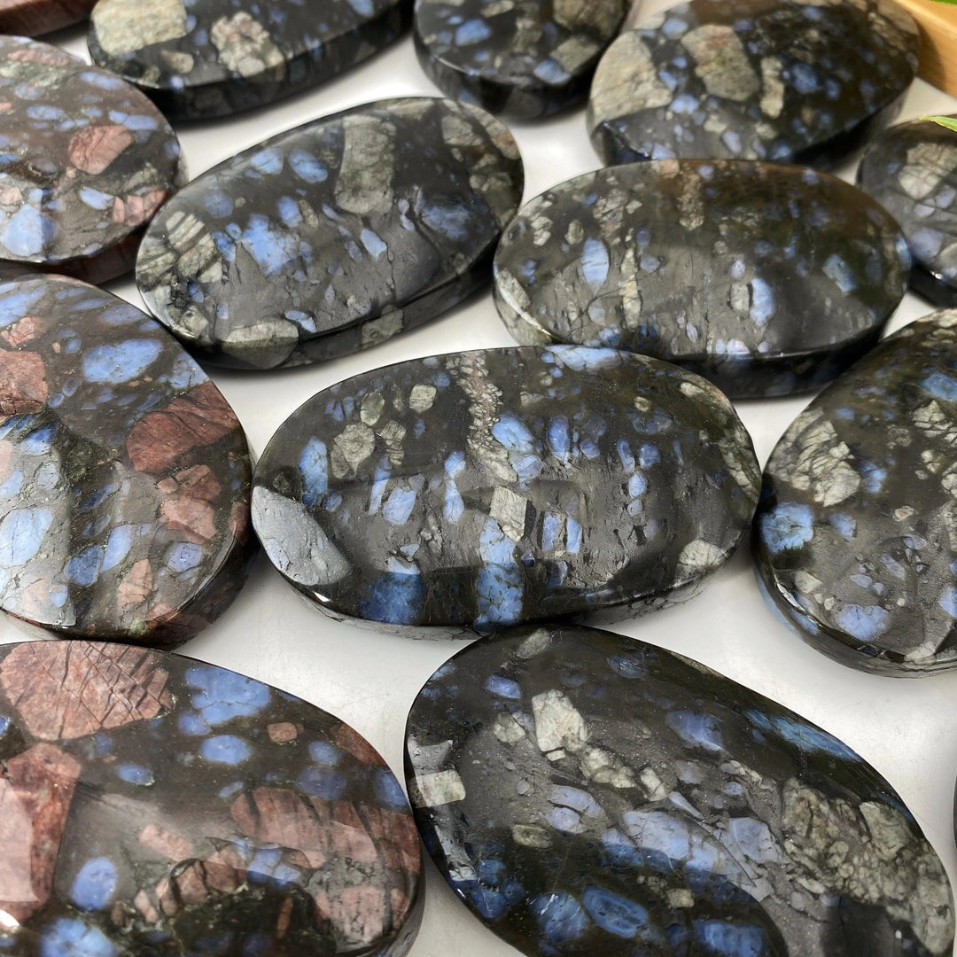 Polished Que Sera stone palm stones with blue, grey, and pink flecks for healing and decor.