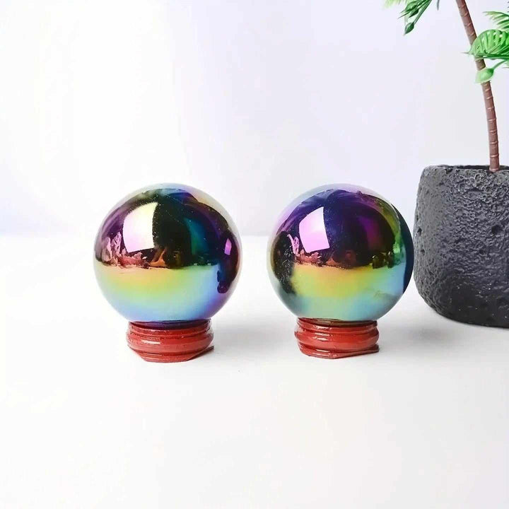 Two Rainbow Aura Obsidian crystal spheres on wooden stands, featuring iridescent violet, gold, and teal volcanic surfaces.