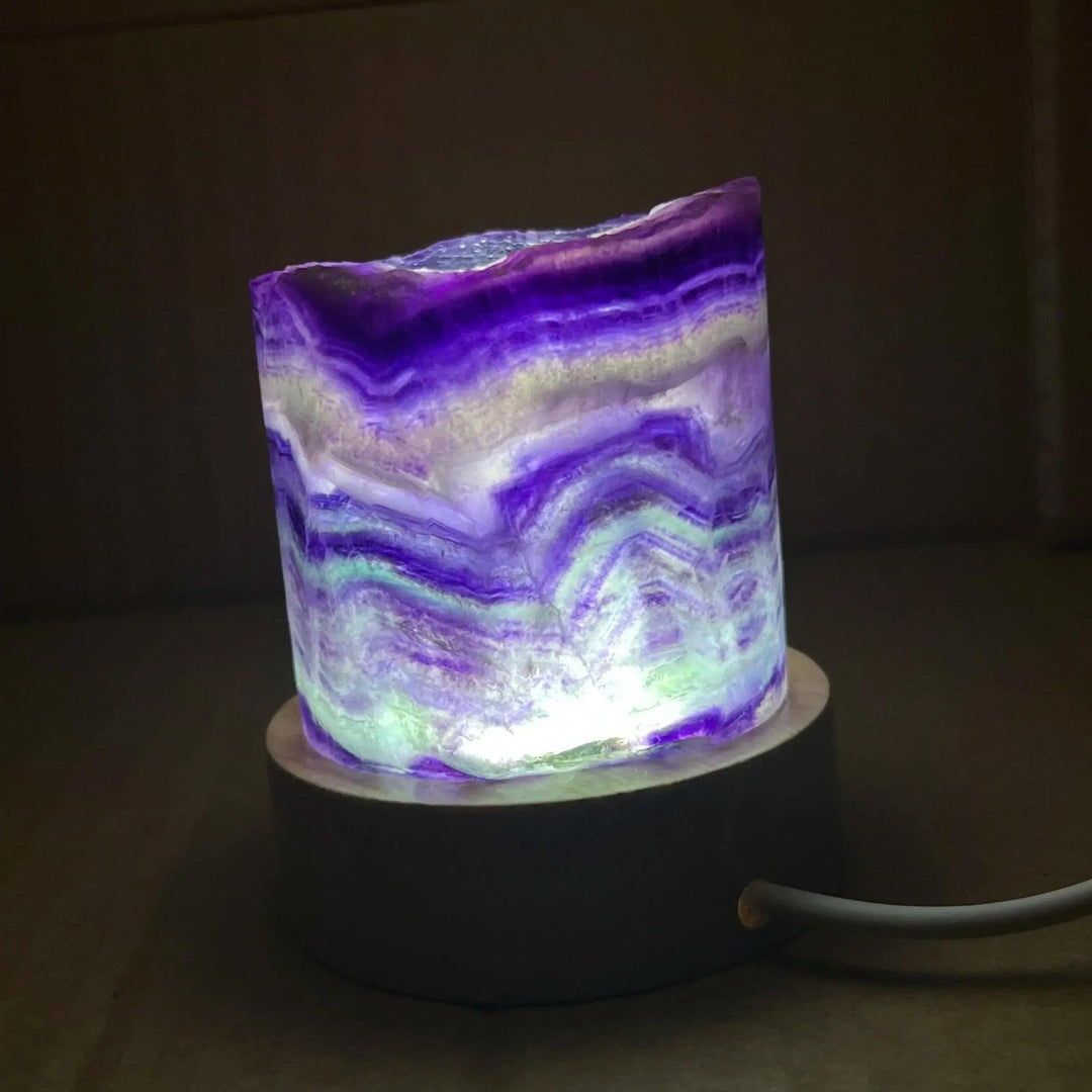 Stunning Rainbow Fluorite Crystal Light Lamp with mesmerizing purple, green, and clear bands, illuminated for a soft glow.