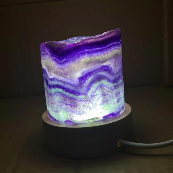 Stunning Rainbow Fluorite Crystal Light Lamp with mesmerizing purple, green, and clear bands, illuminated for a soft glow.