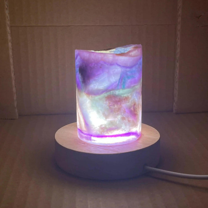 Mesmerizing Rainbow Fluorite Crystal Light Lamp with glowing purple, green, and blue hues on a wooden base.