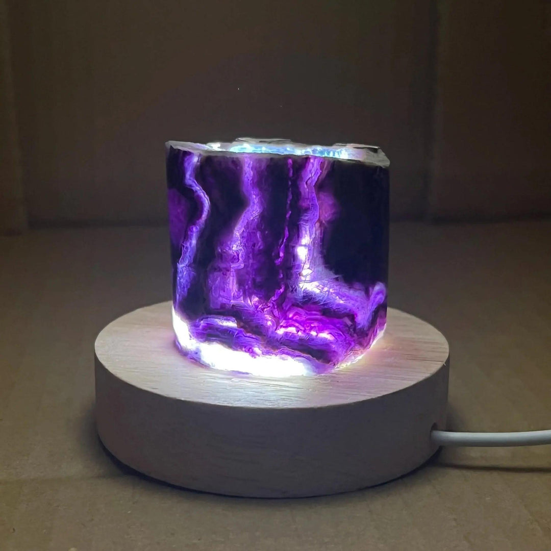 Stunning Rainbow Fluorite Crystal Light Lamp with vibrant purple bands, illuminated on a wooden base for clarity and balance.