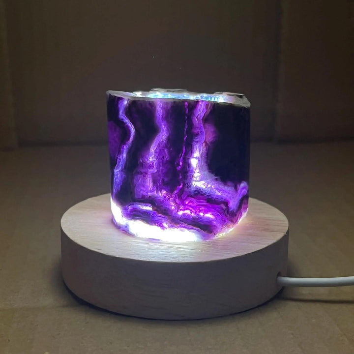 Stunning Rainbow Fluorite Crystal Light Lamp with vibrant purple bands, illuminated on a wooden base for clarity and balance.