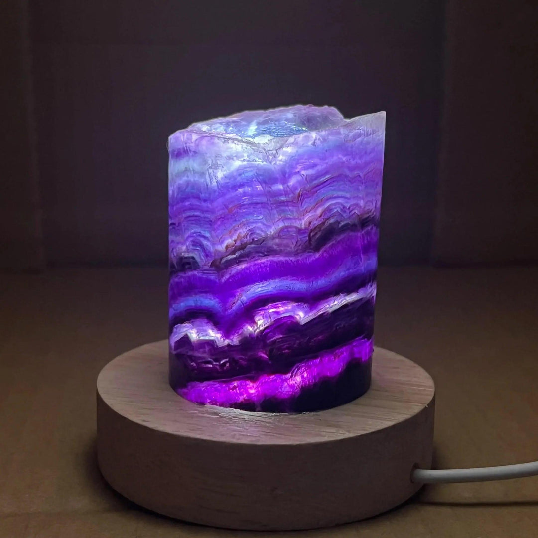 Stunning Rainbow Fluorite Crystal Light Lamp with mesmerizing purple, green, and clear bands, illuminated on a wood base.