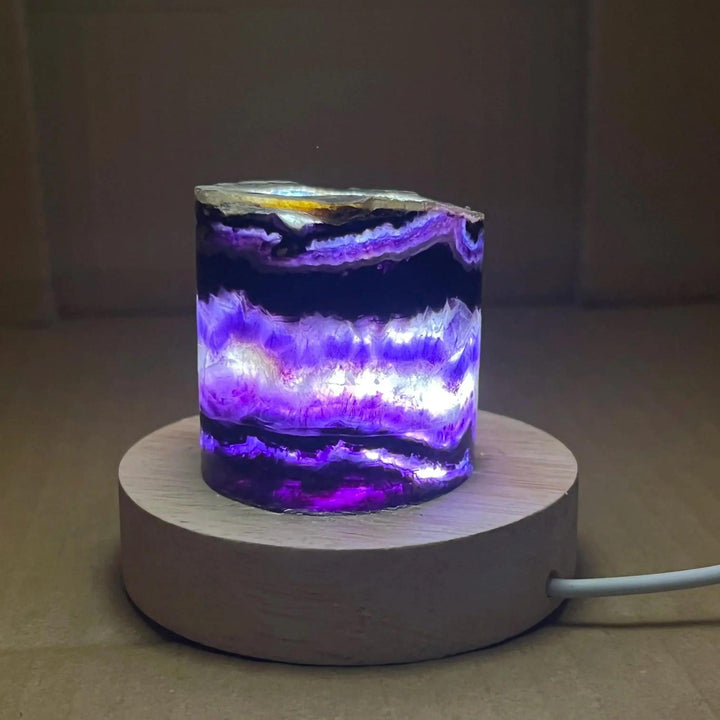 Rainbow Fluorite Crystal Light Lamp with mesmerizing purple, green, and clear bands, illuminated on a wooden base.