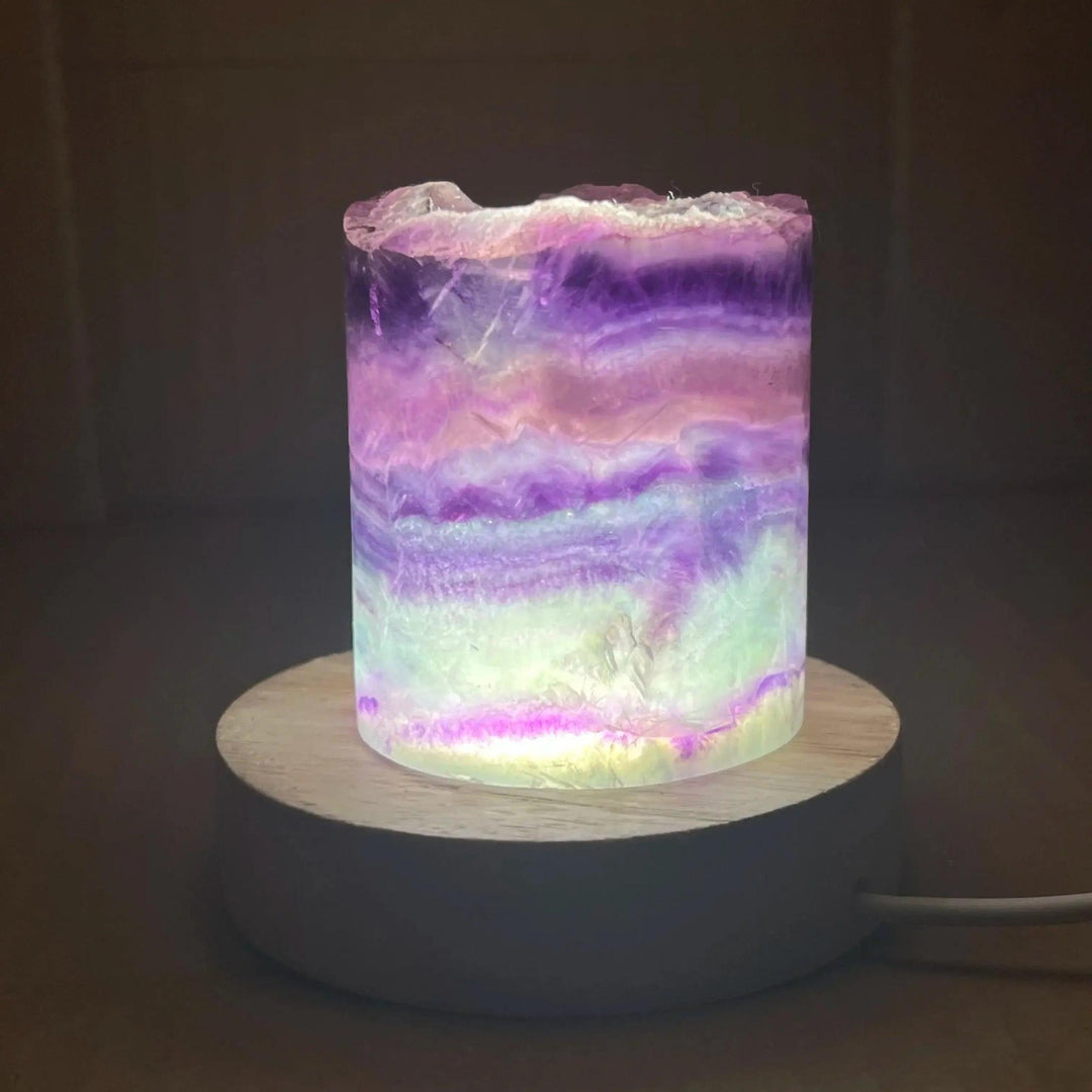 Rainbow Fluorite Crystal Light Lamp with mesmerizing purple, green, and clear bands, illuminated on a wooden base.