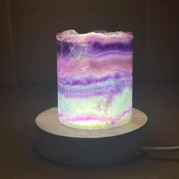 Rainbow Fluorite Crystal Light Lamp with mesmerizing purple, green, and clear bands, illuminated on a wooden base.