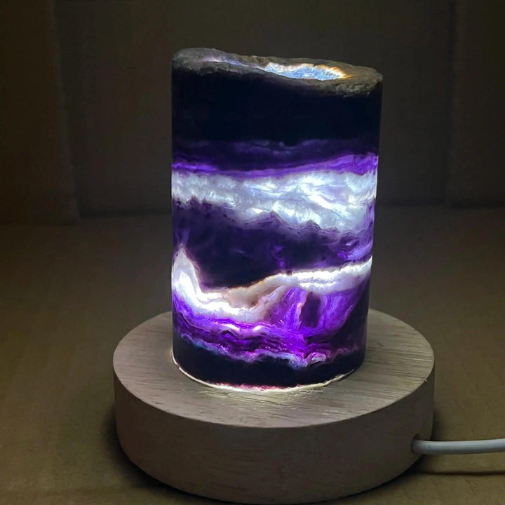 Rainbow Fluorite Crystal Light Lamp with mesmerizing purple, white, and clear bands, illuminated on a wooden base.