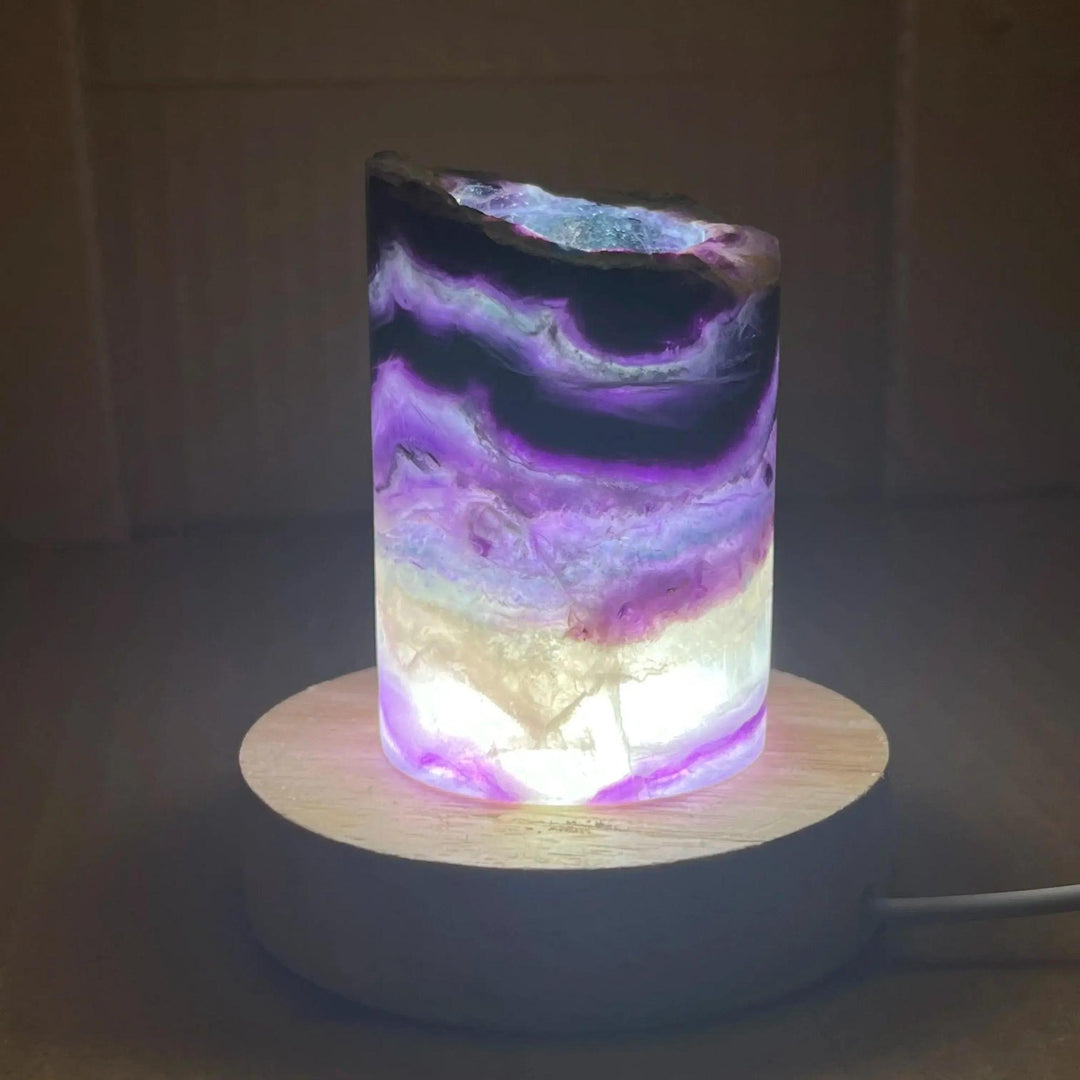 Rainbow Fluorite Crystal Light Lamp with mesmerizing purple, green, and clear bands, illuminated on a wooden base.
