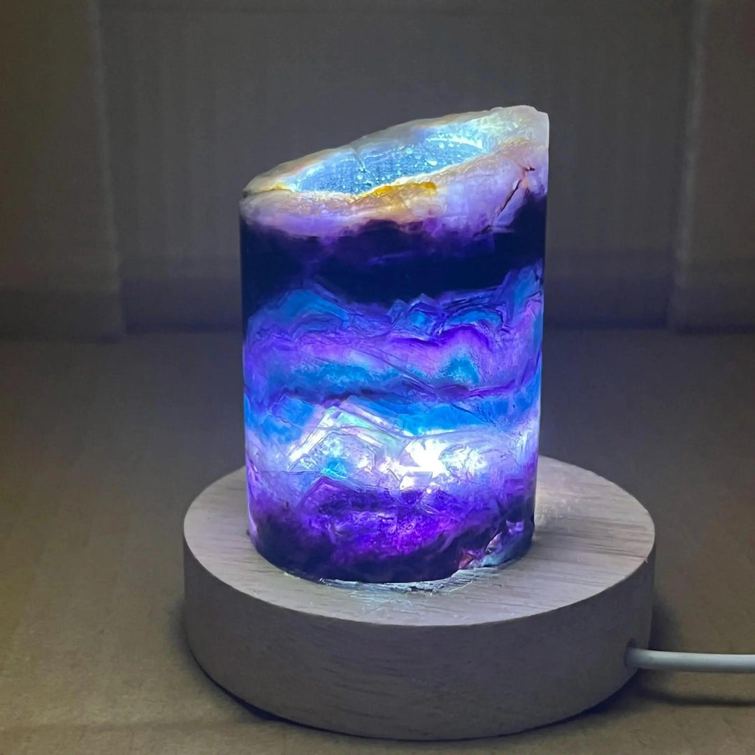 Rainbow Fluorite Crystal Light Lamp with mesmerizing purple, green, and blue bands, illuminated on a wooden base.