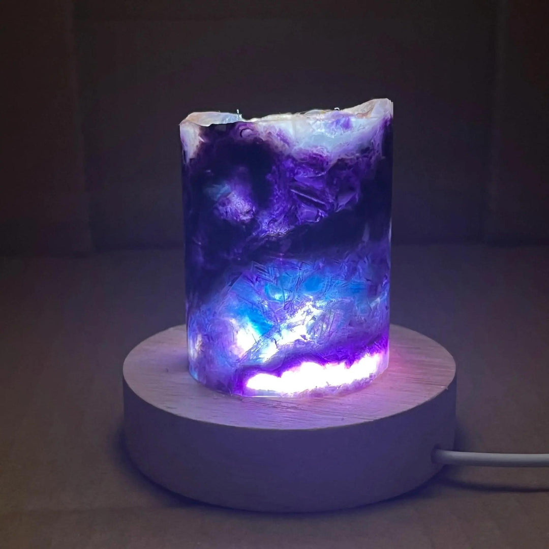 Rainbow Fluorite Crystal Light Lamp with mesmerizing purple, blue, and clear bands, illuminated on a wooden base.