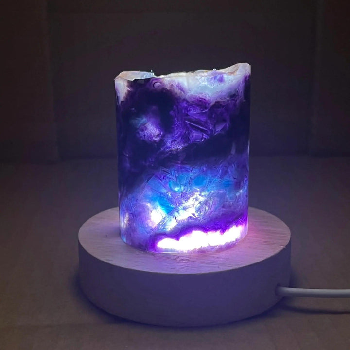 Rainbow Fluorite Crystal Light Lamp with mesmerizing purple, blue, and clear bands, illuminated on a wooden base.