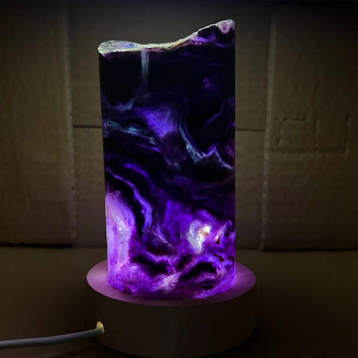 Stunning Rainbow Fluorite Crystal Light Lamp with mesmerizing purple, green, and blue bands, glowing on a wooden base.