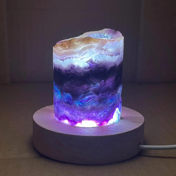 Rainbow Fluorite Crystal Light Lamp with mesmerizing purple, green, and blue bands, illuminated on a wooden base.