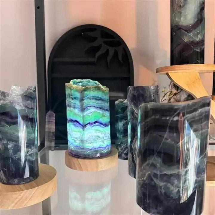 Polished rainbow fluorite crystal lamps with vibrant green and purple banding on wooden bases for meditation and decor.