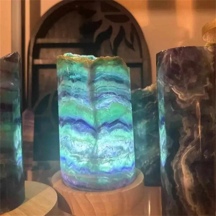 Polished Rainbow Fluorite crystal lamp with vibrant green and purple banding, glowing on a wooden base for energy healing.