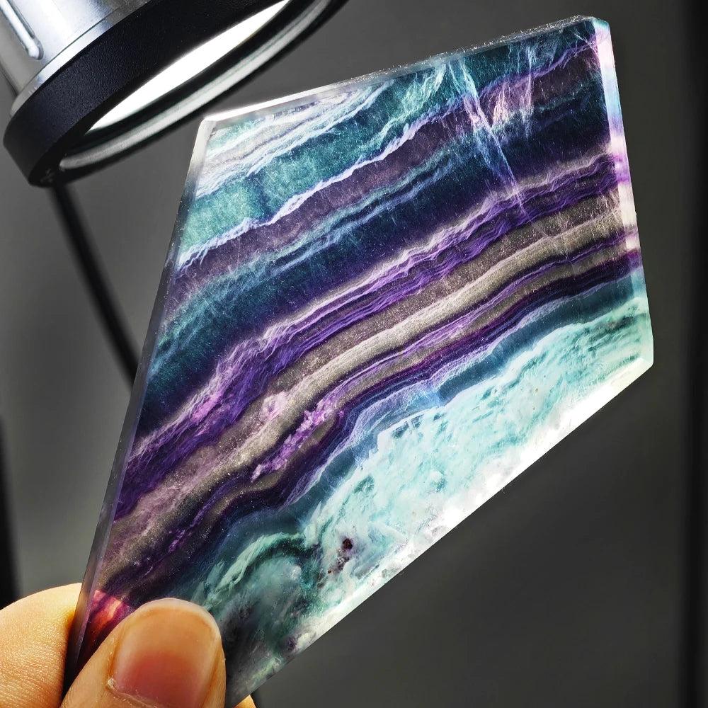 Polished natural rainbow fluorite slice featuring vibrant purple and teal bands, perfect for reiki healing and home decor.