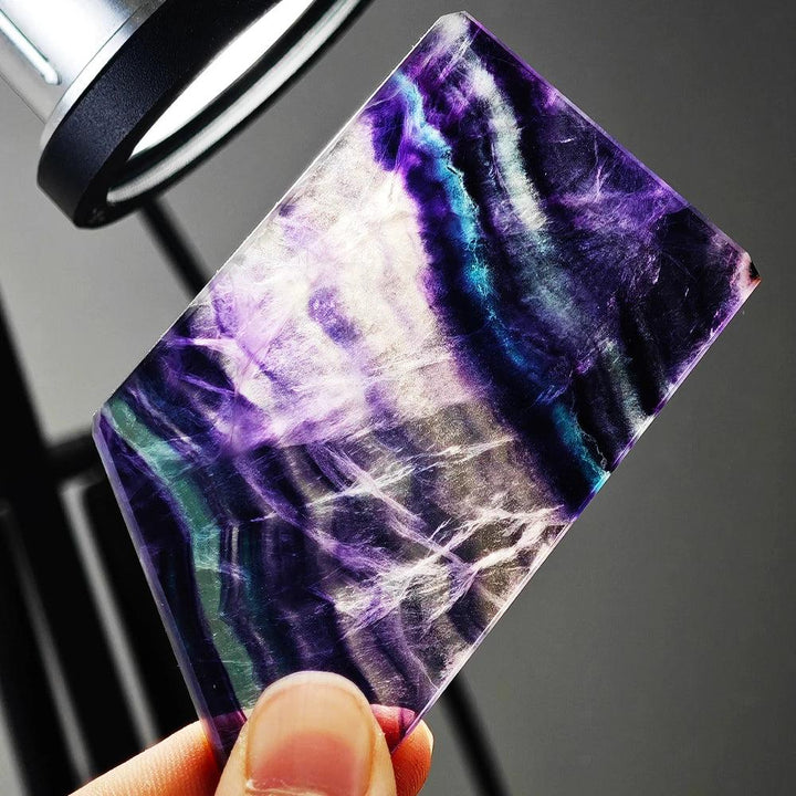 Natural rainbow fluorite slice featuring vibrant purple and blue bands, perfect for reiki healing and spiritual decor.
