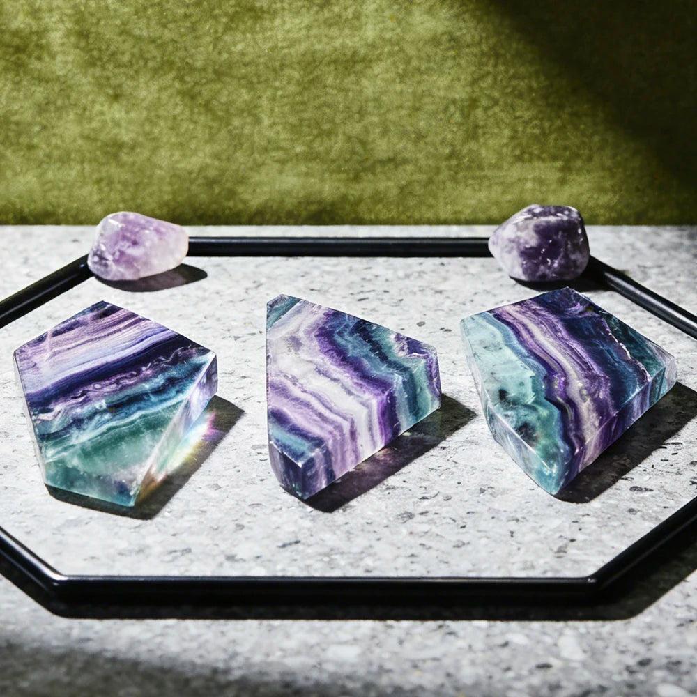 Natural rainbow fluorite crystal slices featuring vibrant purple and green bands, perfect for Reiki healing and decor.