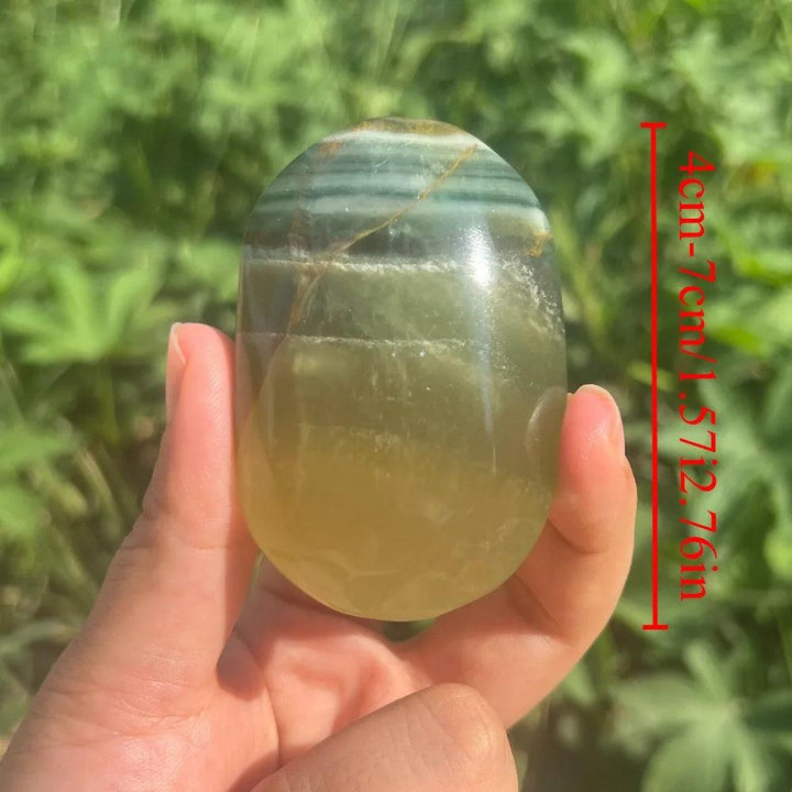 Polished green and yellow rainbow mango fluorite healing crystal palm stone held in hand.
