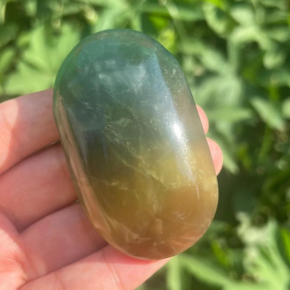 Polished green and yellow rainbow mango fluorite healing crystal palm stone held in hand.