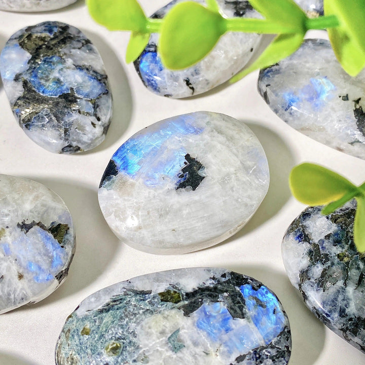 Polished Rainbow Moonstone palm stone with iridescent blue flash and natural mineral inclusions for healing and decor.