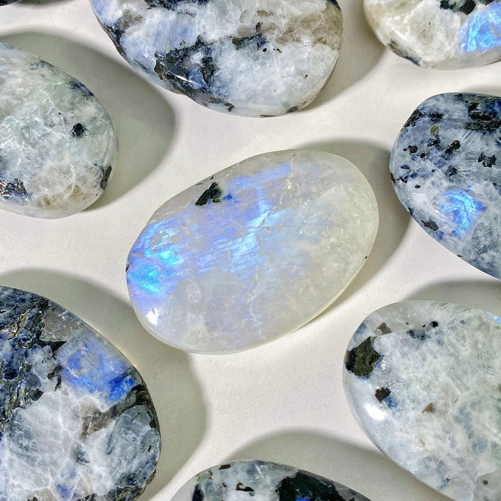 Polished Rainbow Moonstone palm stone with iridescent blue flashes, perfect for healing, meditation, and home decor.