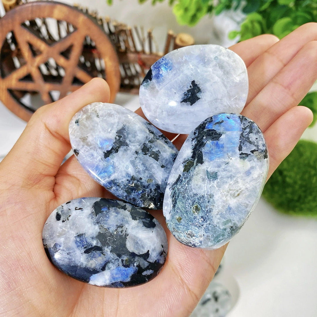 Polished rainbow moonstone palm stones with shimmering blue flashes and natural mineral inclusions for healing.