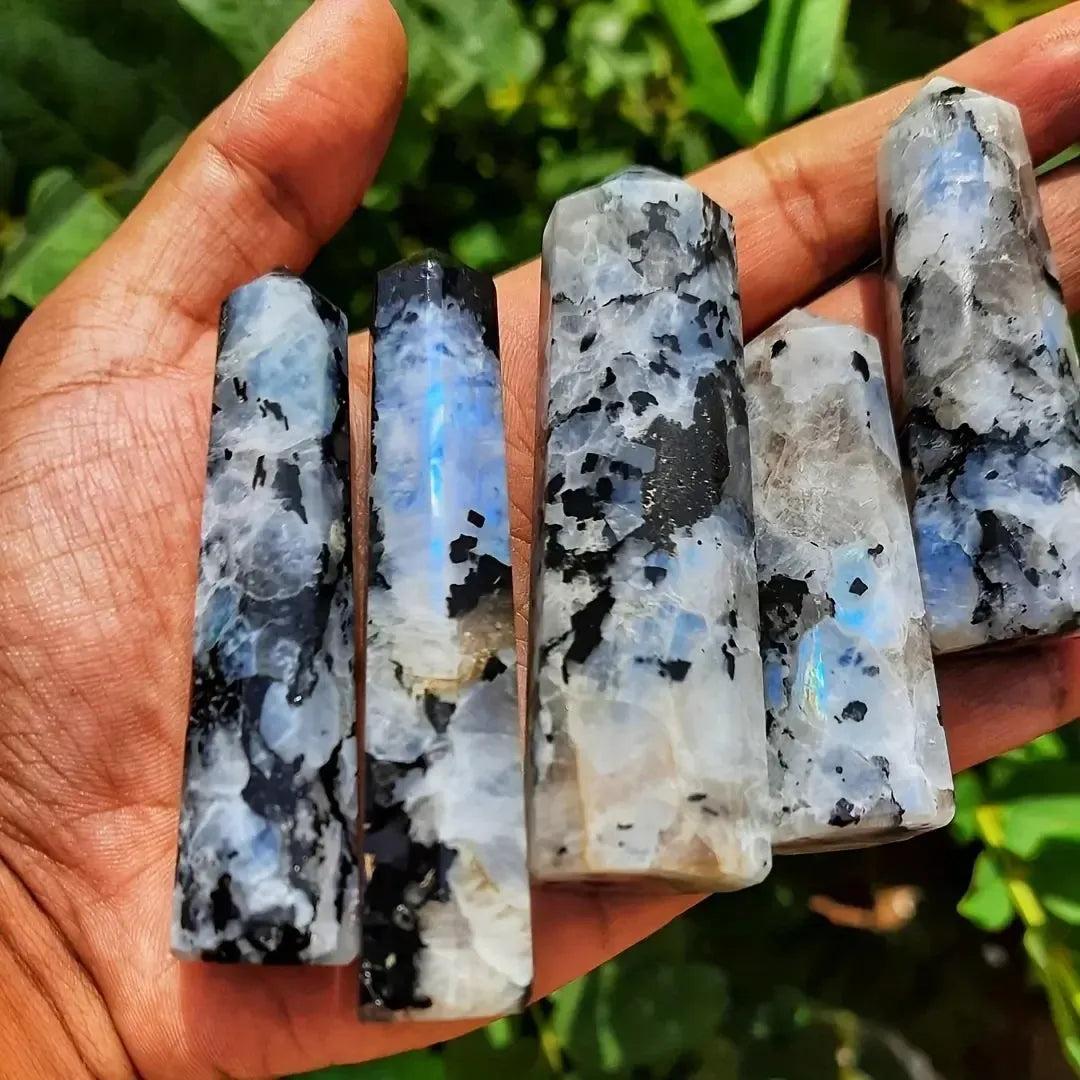 Hand holding five Rainbow Moonstone crystal towers with iridescent blue and black flashes from Crystal Destiny.