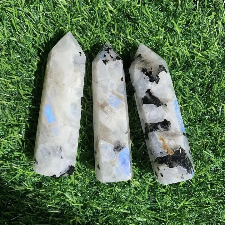 Three iridescent Rainbow Moonstone crystal towers with blue flashes on green grass by Crystal Destiny.