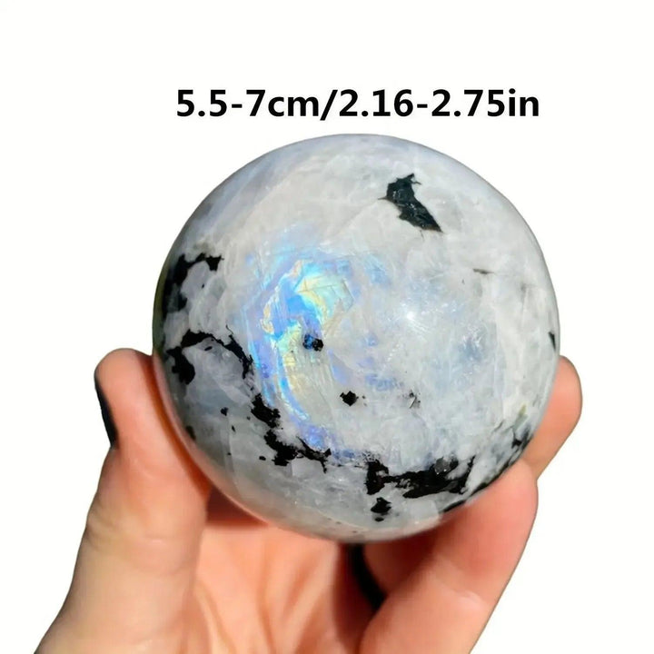 Luminous Rainbow Moonstone sphere from Crystal Destiny, showing blue and rainbow flashes, held in hand.