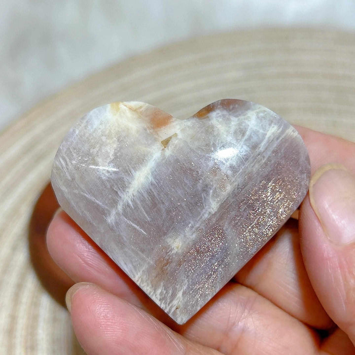 Polished Rainbow Moonstone and Sunstone heart featuring milky white tones, warm orange sparkles, and balancing energy.
