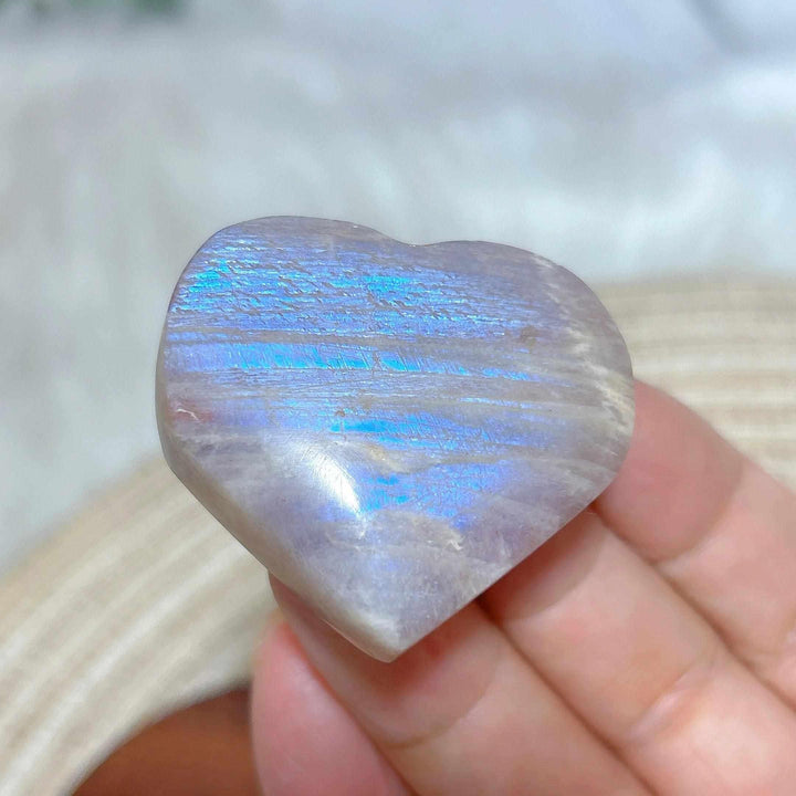 Polished Rainbow Moonstone and Sunstone heart featuring milky white tones and a vibrant, glowing blue flash.