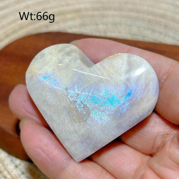 Polished rainbow moonstone and sunstone heart with milky white tones, orange hues, and a vibrant blue flash.