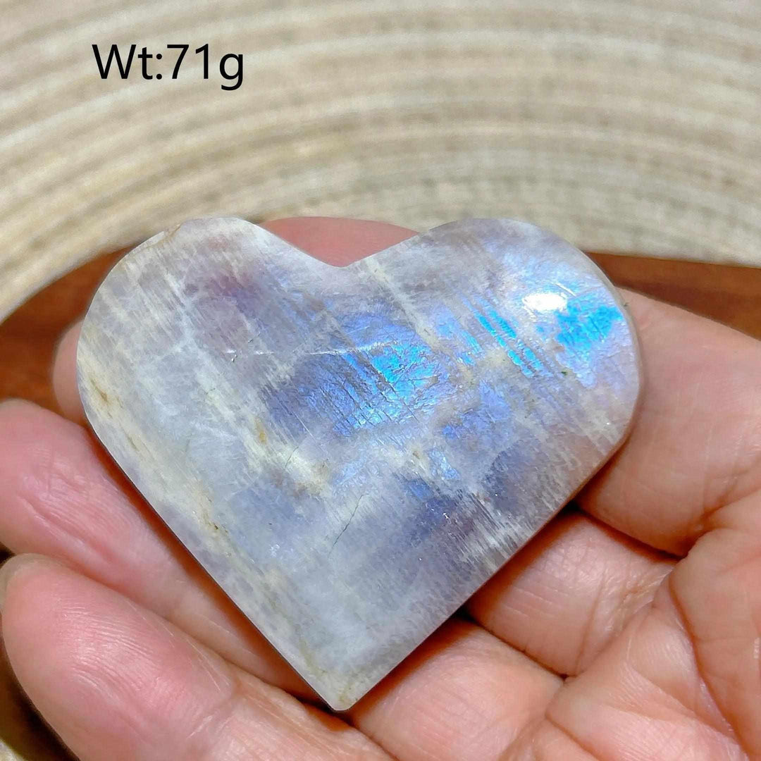Polished Rainbow Moonstone and Sunstone heart with milky white tones and vibrant blue flashes, weighing 71g.