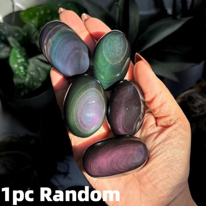 Smooth Rainbow Obsidian palm stone with glossy black finish and vibrant purple, green, and gold iridescent bands.