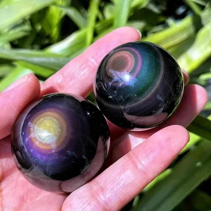 Two polished Rainbow Obsidian spheres showing vibrant, iridescent bands of color for root chakra protection and reflection.