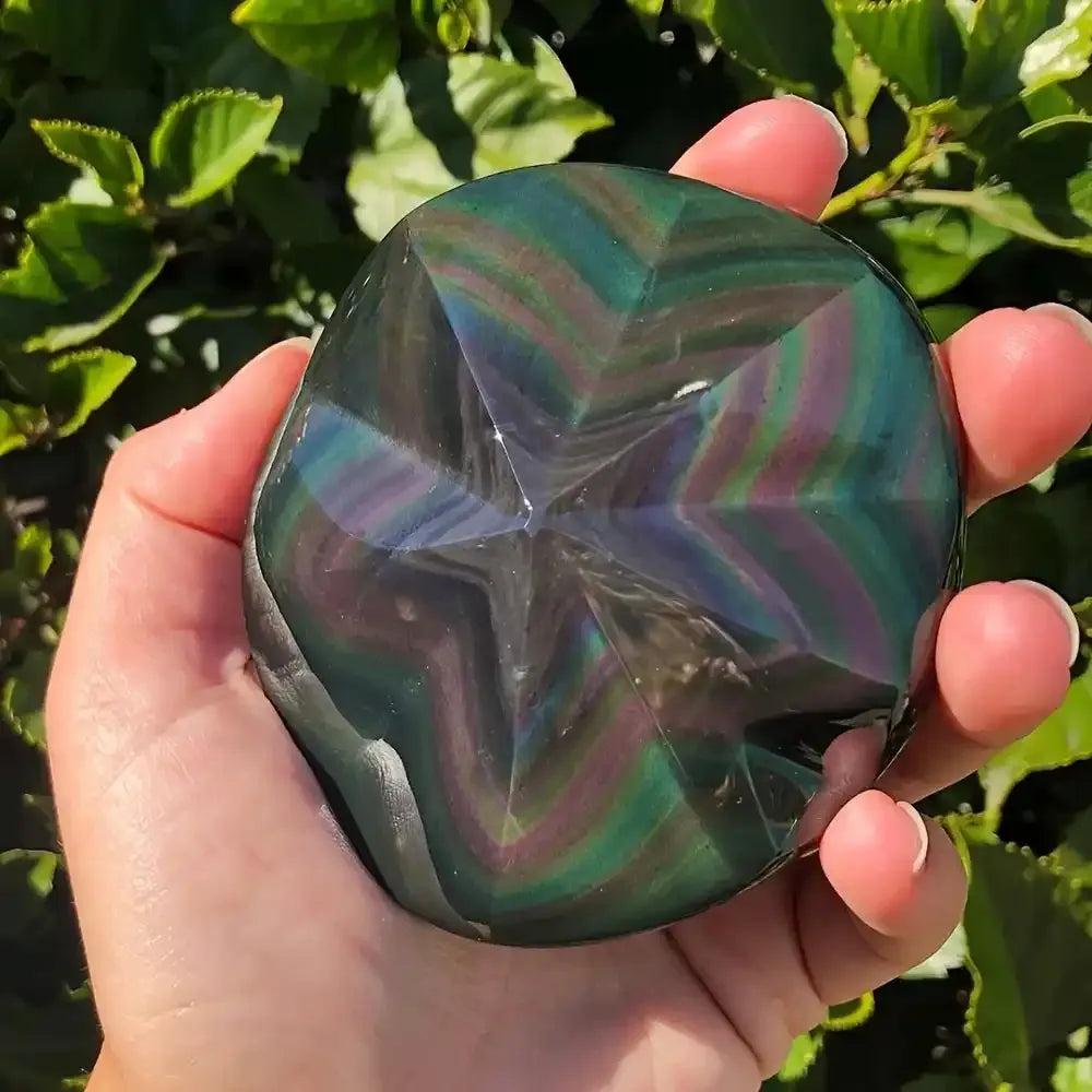 Hand-carved Rainbow Obsidian star showing vibrant purple, green, and gold flashes for grounding and protection.