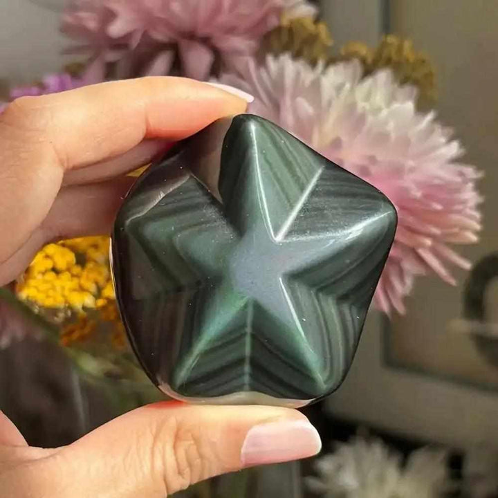 Hand-carved Rainbow Obsidian star with a polished black finish and shimmering green, gold, and purple protective energy.