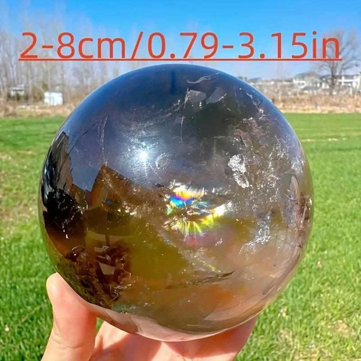Polished Rainbow Smoky Quartz sphere in smoky gray with internal rainbow flashes for grounding and root chakra healing.