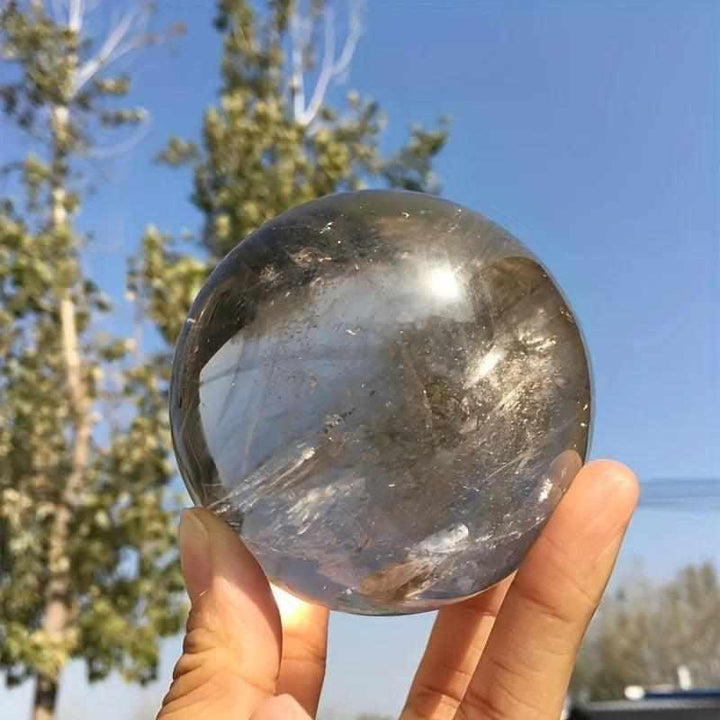 Polished Rainbow Smoky Quartz sphere in warm brown and gray, featuring internal rainbows for grounding and energy healing.